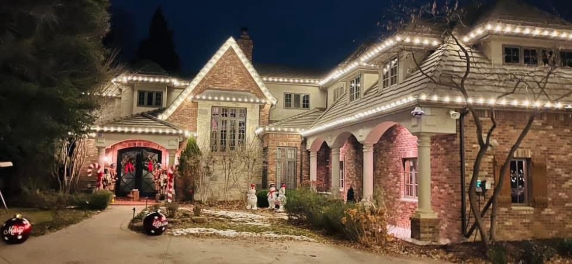 Brick home outlined with professional Christmas lights and festive yard décor